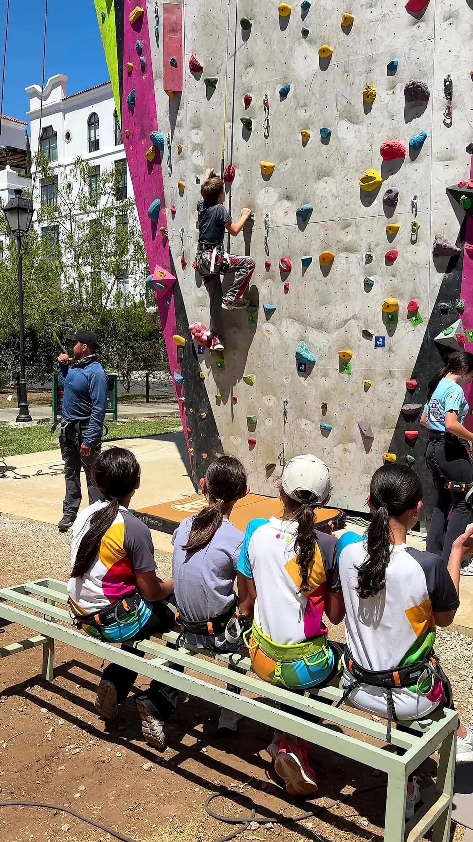 Alumnas de excursión con arneses, esperando su turno mientras una compañera escala El Muro
