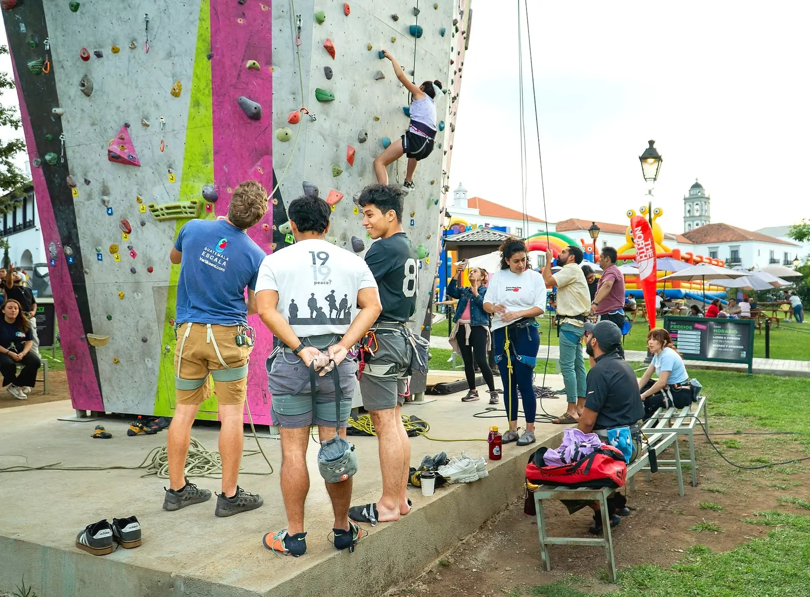 Grupo al pie de El Muro durante un evento, mirando a un escalador cerca de la cima